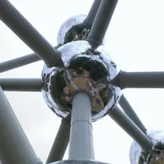 Close-up of the Atomium's shiny spheres and steel tubes against a slightly cloudy sky.