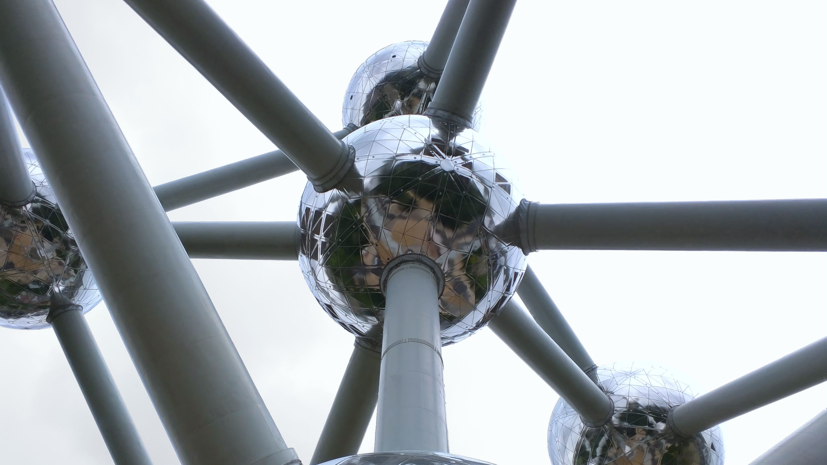 Close-up of the Atomium's shiny spheres and steel tubes against a slightly cloudy sky.